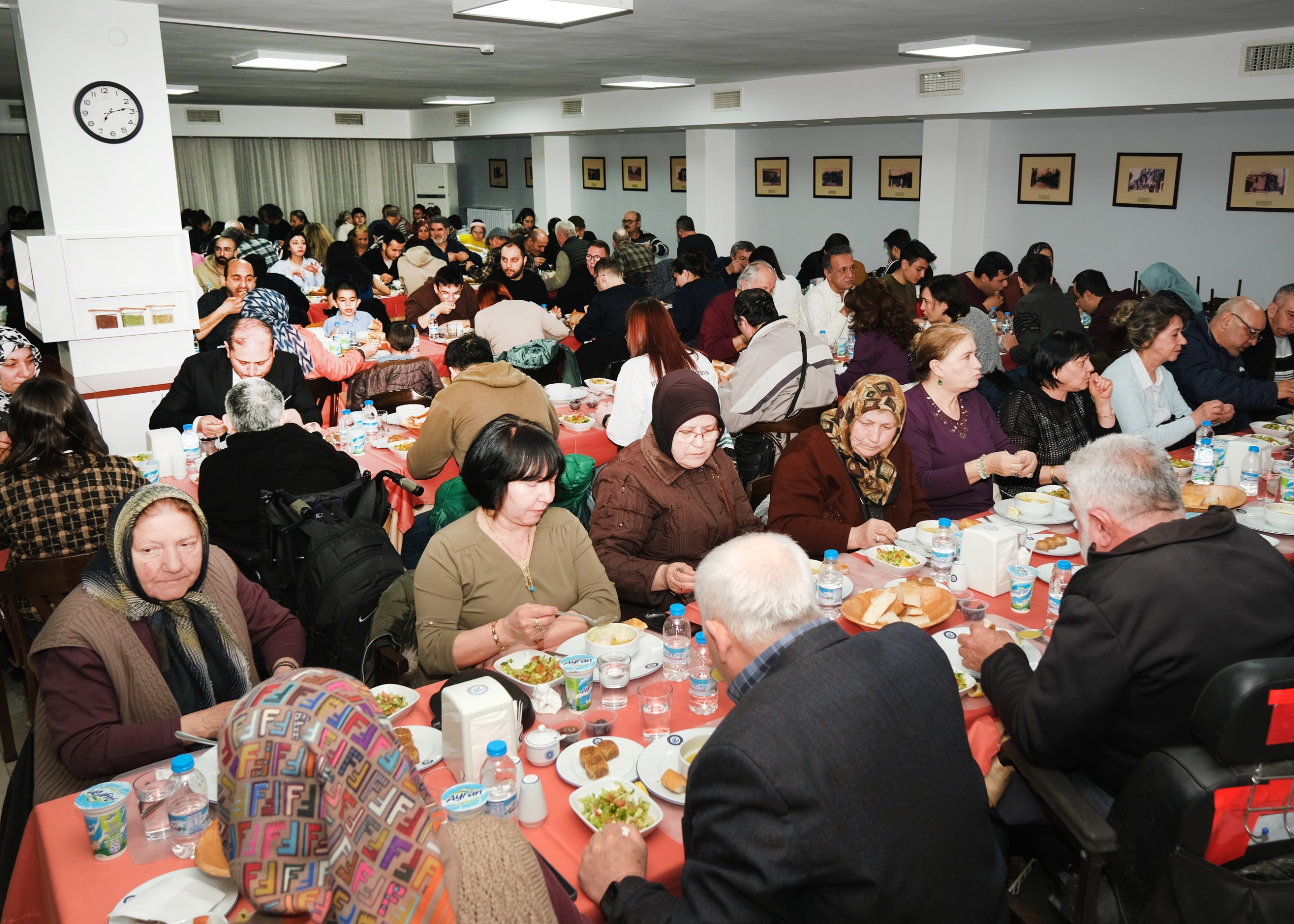 Eskişehir Büyükşehir Belediyesi’nin geleneksel hale gelen iftar buluşmaları kent merkezi ve kırsal ilçelerde başladı. Başkan Büyükerşen, engelli bireyler ve ailelerini ağırlarken Mahmudiye’de de ilçe sakinleri aynı sofrada bir araya geldi.

Eskişehir Büyükşehir Belediyesi’nin her Ramazan ayında düzenlediği geleneksel iftar davetleri bu yıl da büyük bir katılımla başladı. Buluşmalar kapsamında Eskişehir Büyükşehir Belediye Başkanı Prof. Dr. Yılmaz Büyükerşen engelli dernekleri, üyeler ve ailelerini iftar yemeğinde ağırladı.
Büyükşehir Belediyesi yemekhanesinde gerçekleşen daveteBüyükerşen’in yanı sıra CHP Eskişehir Milletvekili Jale Nur Süllü, CHP 27. dönem Hatay Milletvekili Suzan Şahin ve 27. dönem Samsun Milletvekili Neslihan Hancıoğlu, belediye bürokratları, engelli bireyler ve aileleri katıldı.
Engelli bireylere ve ailelerine davete katıldıkları için teşekkür eden Büyükerşen, “Engelli dostu, engelleri aşan bir şehir için hep birlikte mücadele ettik. Sizlere, fedakâr ailelerinize çok teşekkür ediyorum. Nice Ramazanlara, nice bayramlara hep birlikte ulaşmak dileğiyle diyor; şimdiden bayramınızı tebrik ediyorum.” dedi.

Engelli bireyler ve aileleri, Büyükerşen’in her zaman yanlarında olduğunu ifade ederek kendilerine verdiği destekler için teşekkür ettiler. İftar yemeği sonrası Başkan Büyükerşen, engelli bireyler ve aileleri ile tek tek sohbet etti.
İlk iftarın bir diğer buluşma noktası ise Mahmudiye ilçesi oldu. Büyükşehir Belediyesince Mahmudiye Kapalı Pazar Yerinde düzenlenen iftar programına Mahmudiye Belediye Başkanı İshak Gündoğan, Büyükşehir Belediyesi Genel Sekreter Vekili M. Recai Erdir, belediye bürokratları, meclis üyeleri, muhtarlar ile ilçe sakinleri katıldı. Gündoğan ve Erdir, vatandaşların Ramazanını tebrik ederek birlikte iftar yaptılar. Kent merkezi ve ilçelerde düzenlenen iftar programları Ramazan boyunca devam edecek.
