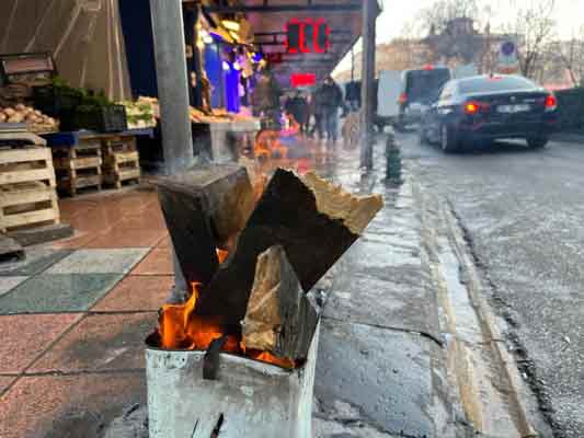 Dükkanlarının önüne koydukları tenekelerin içinde odun yakan esnaf, geçici süre de olsa ısınmak için ateş başında toplandı.